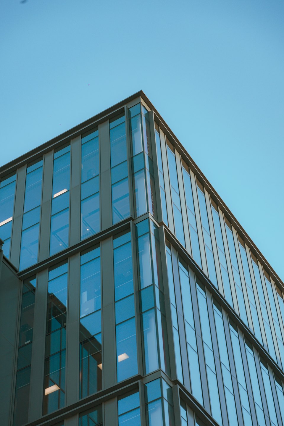 Modern corporate building with glass windows reflecting the clear sky.