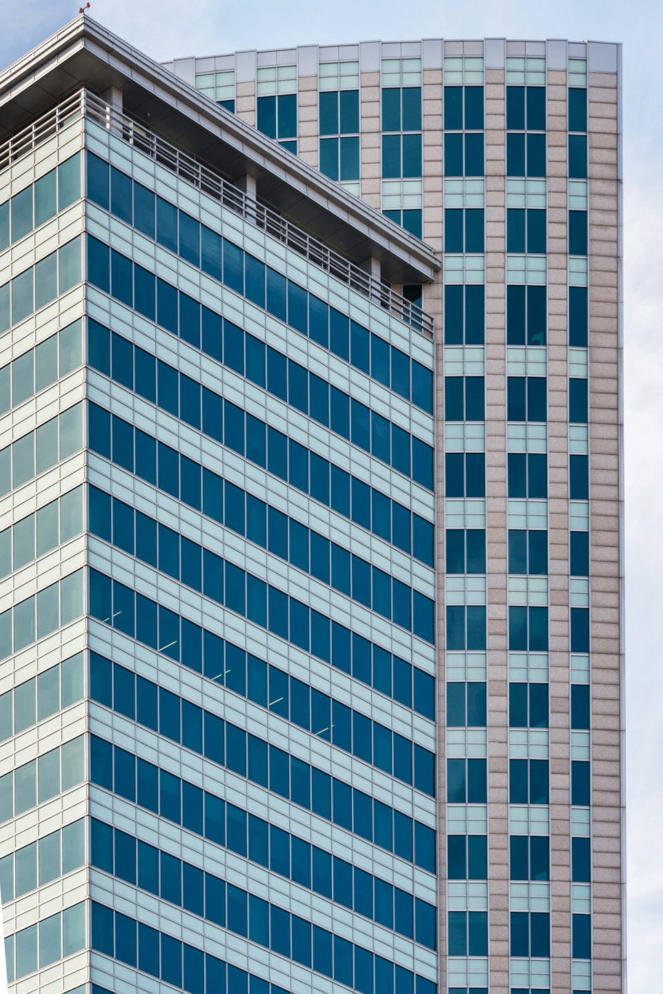 Two modern office buildings with glass and stone facades stand together.